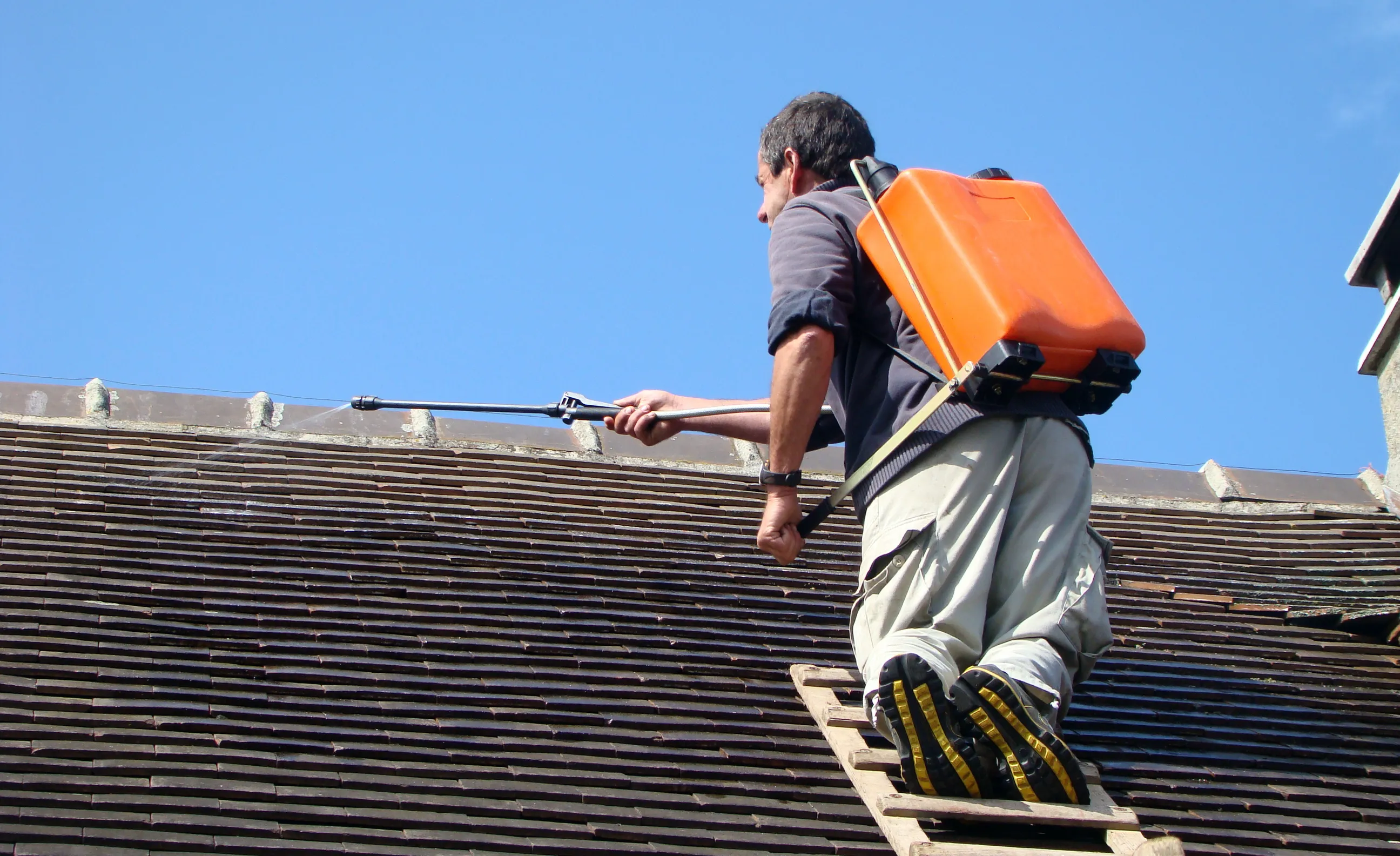 Homme pulvérisant un toit